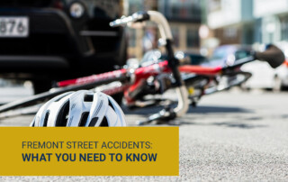Bicycle helmet on the ground with parked bikes and city street in background; yellow caption reads Fremont Street Accidents: What You Need to Know.